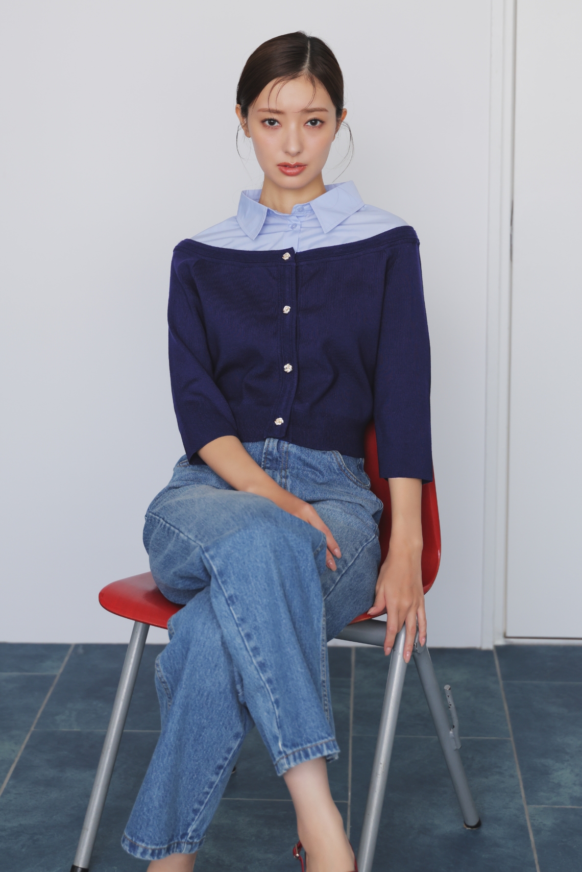 シャツレイヤードライクニット・ストレートデニムパンツ・ストラップバックスリングパンプスを着用した女性