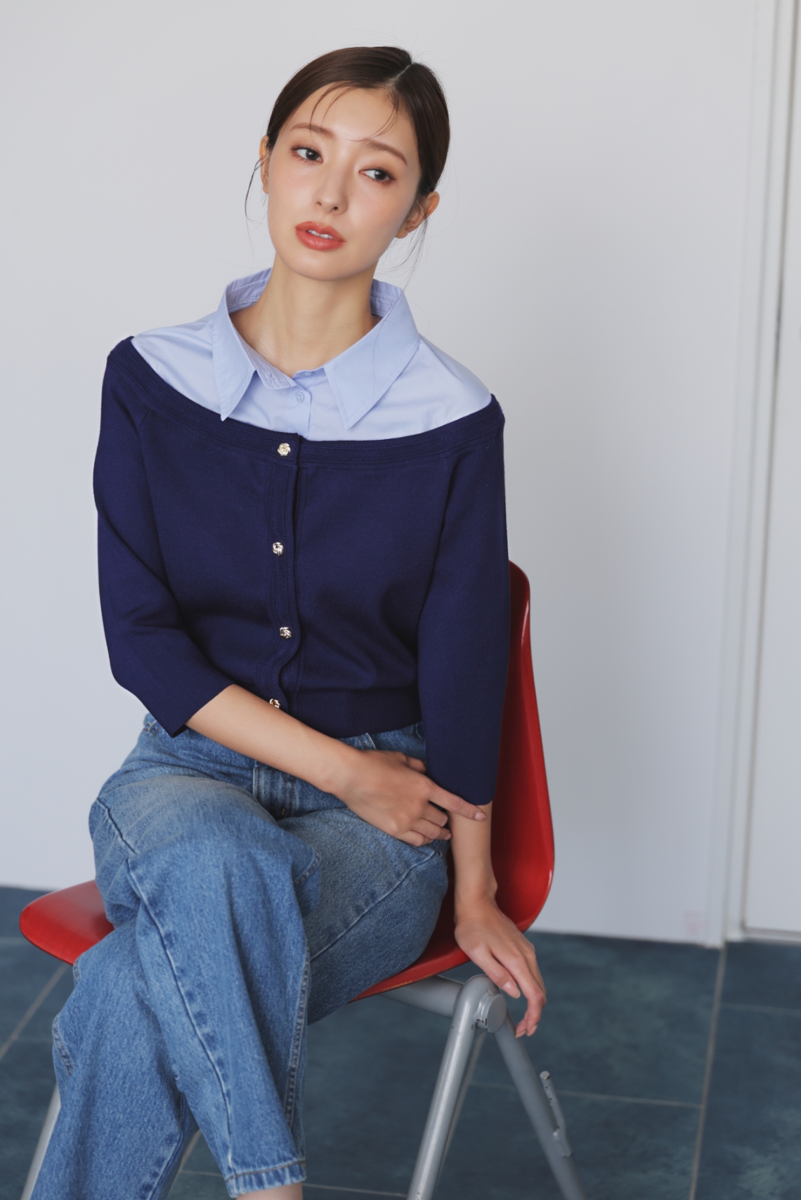 シャツレイヤードライクニット・ストレートデニムパンツ・ストラップバックスリングパンプスを着用した女性