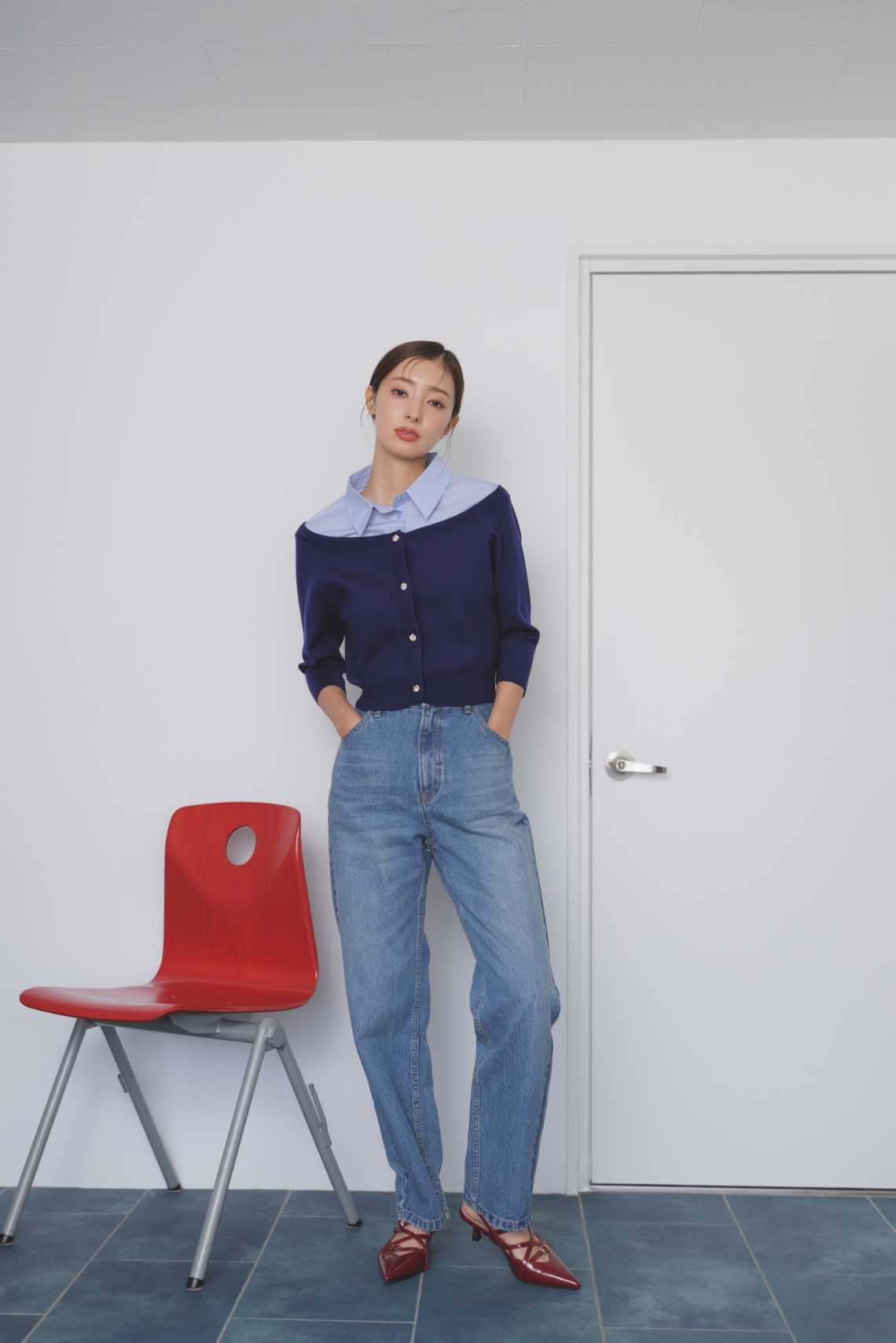 シャツレイヤードライクニット・ストレートデニムパンツ・ストラップバックスリングパンプスを着用した女性
