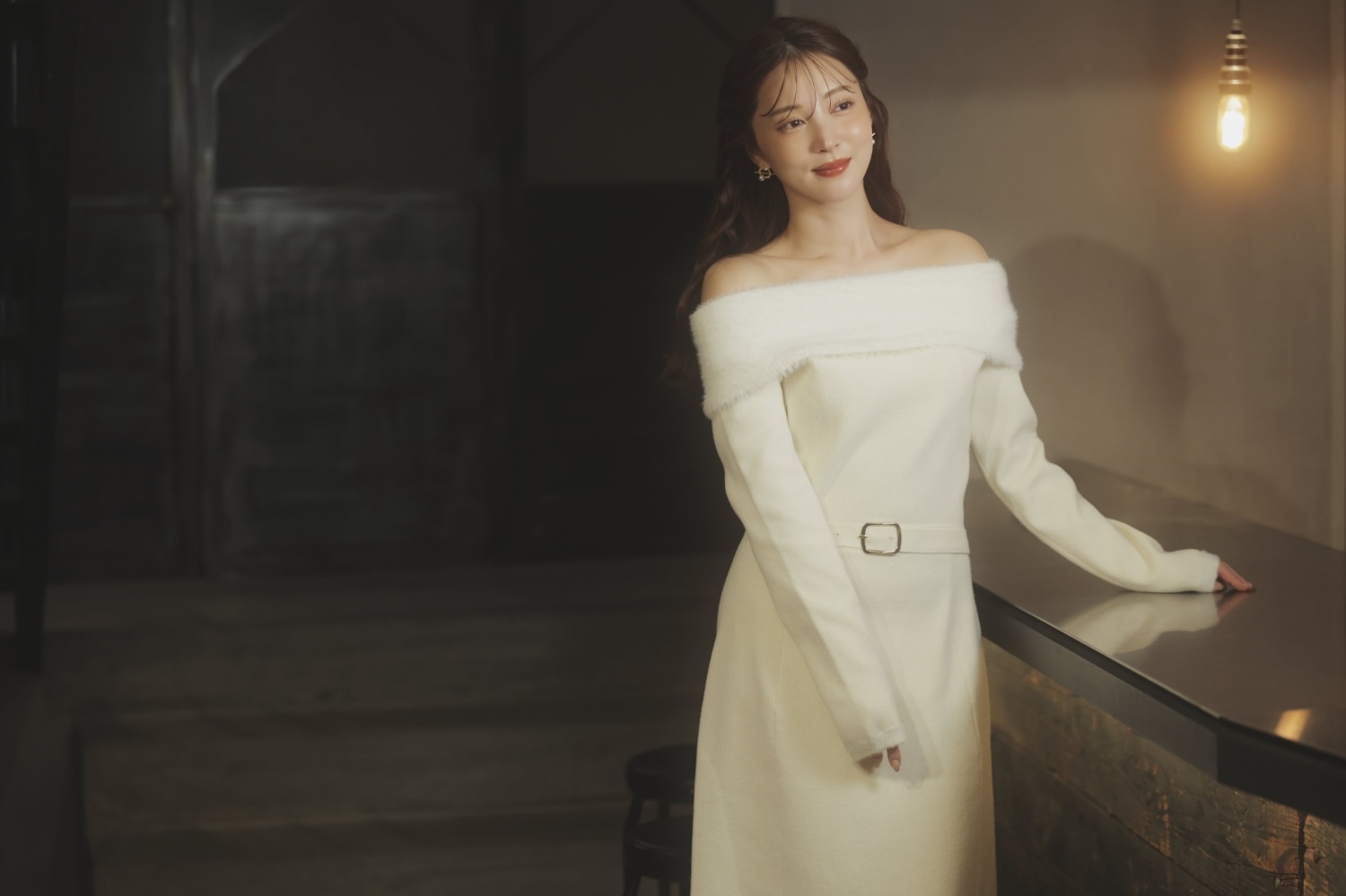 フェザートリム配色ドッキングワンピース・サークルモチーフピアスを着用した女性