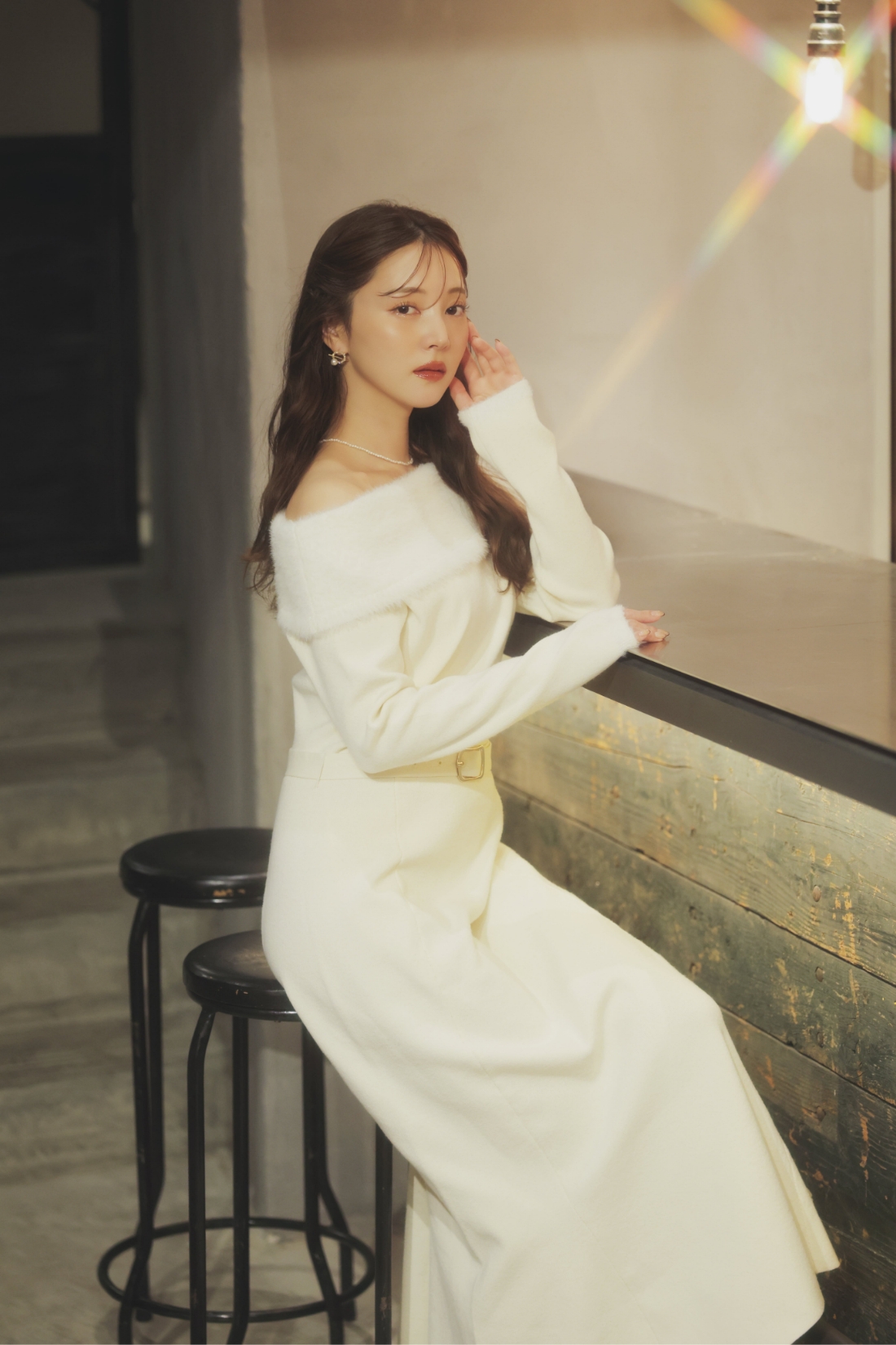 フェザートリム配色ドッキングワンピース・サークルモチーフピアスを着用した女性