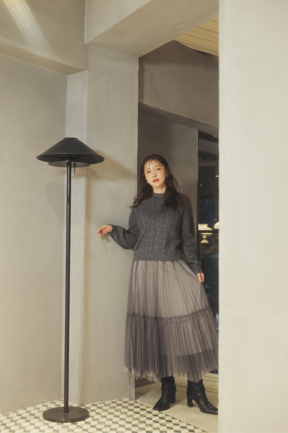 スパンコールラメケーブルニット・グラデイレヘムチュールスカート・ロングブーツ・トリプルビジューピアスを着用した女性