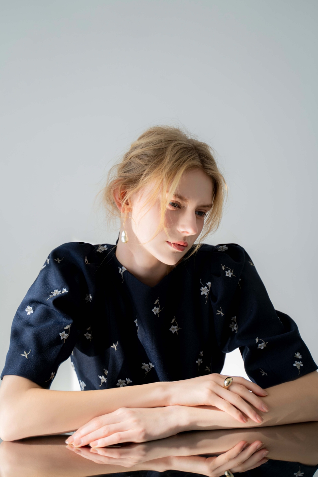 フラワー刺繍ブラウス・バロックパールアシメピアスを着用した女性