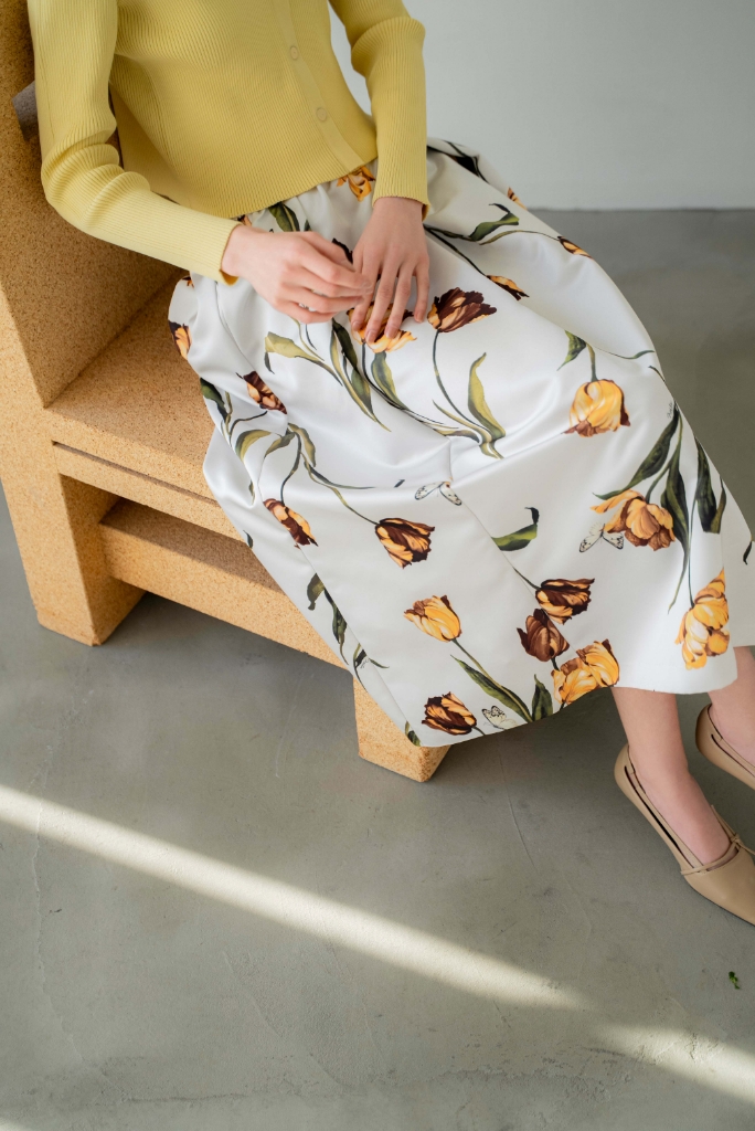 Vネックボタンリブニット・チューリッププリントフレアスカート・サイドノットパンプスを着用した女性の足元