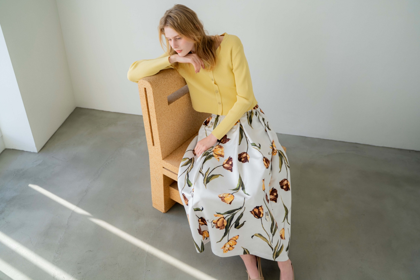 Vネックボタンリブニット・チューリッププリントフレアスカート・サイドノットパンプスを着用した女性