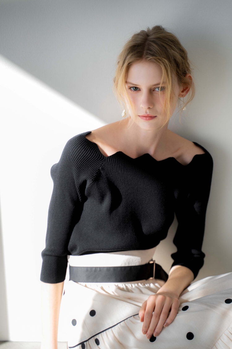 スカラネックデザインニット・ドット刺繍ティアードスカート・バロックパールアシメピアスを着用した女性