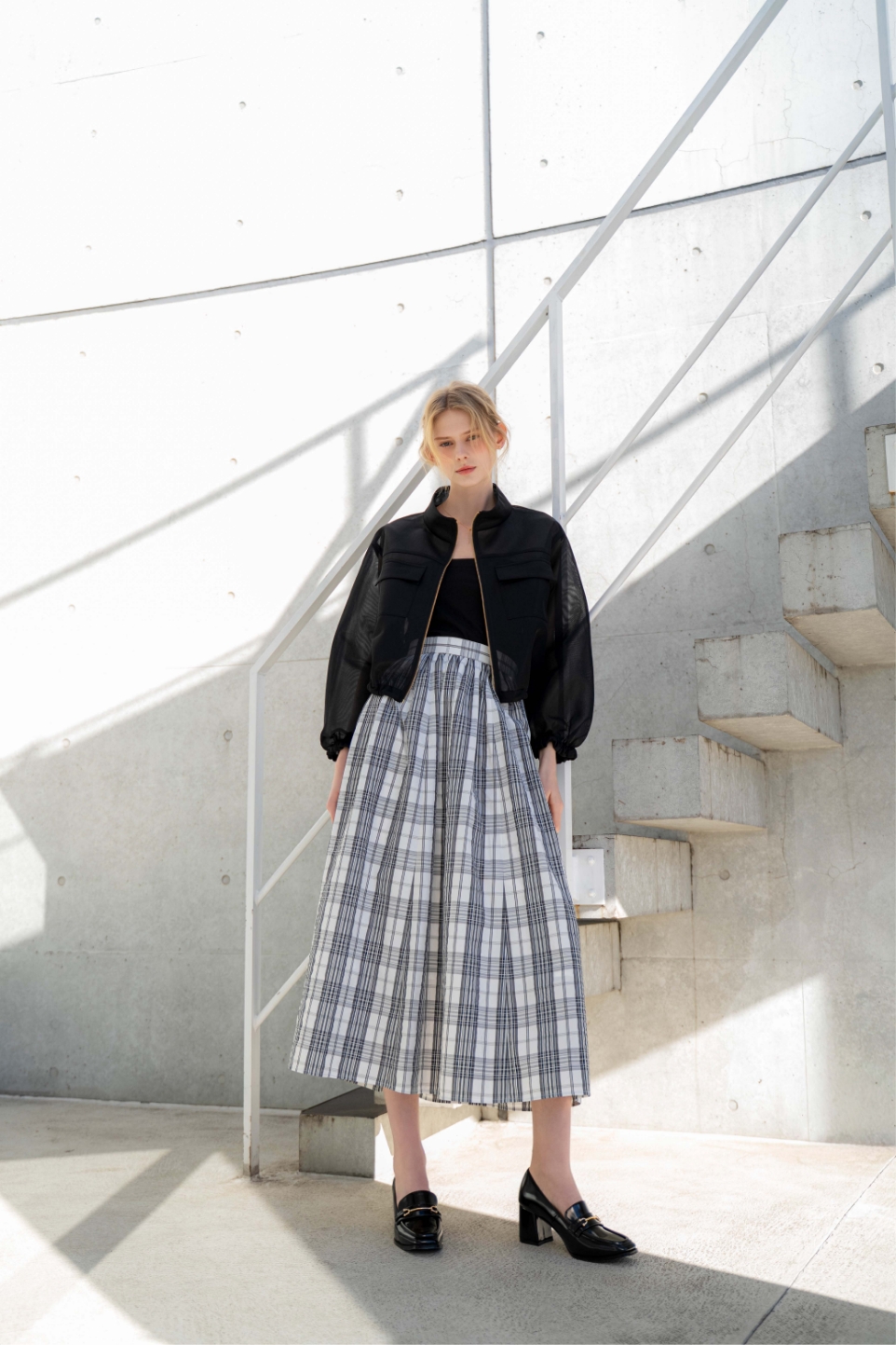 シアーダンボールブルゾン・アソートギャザーフレアスカート・スクエアビットローファー・ビジューラリエットネックレスを着用した女性