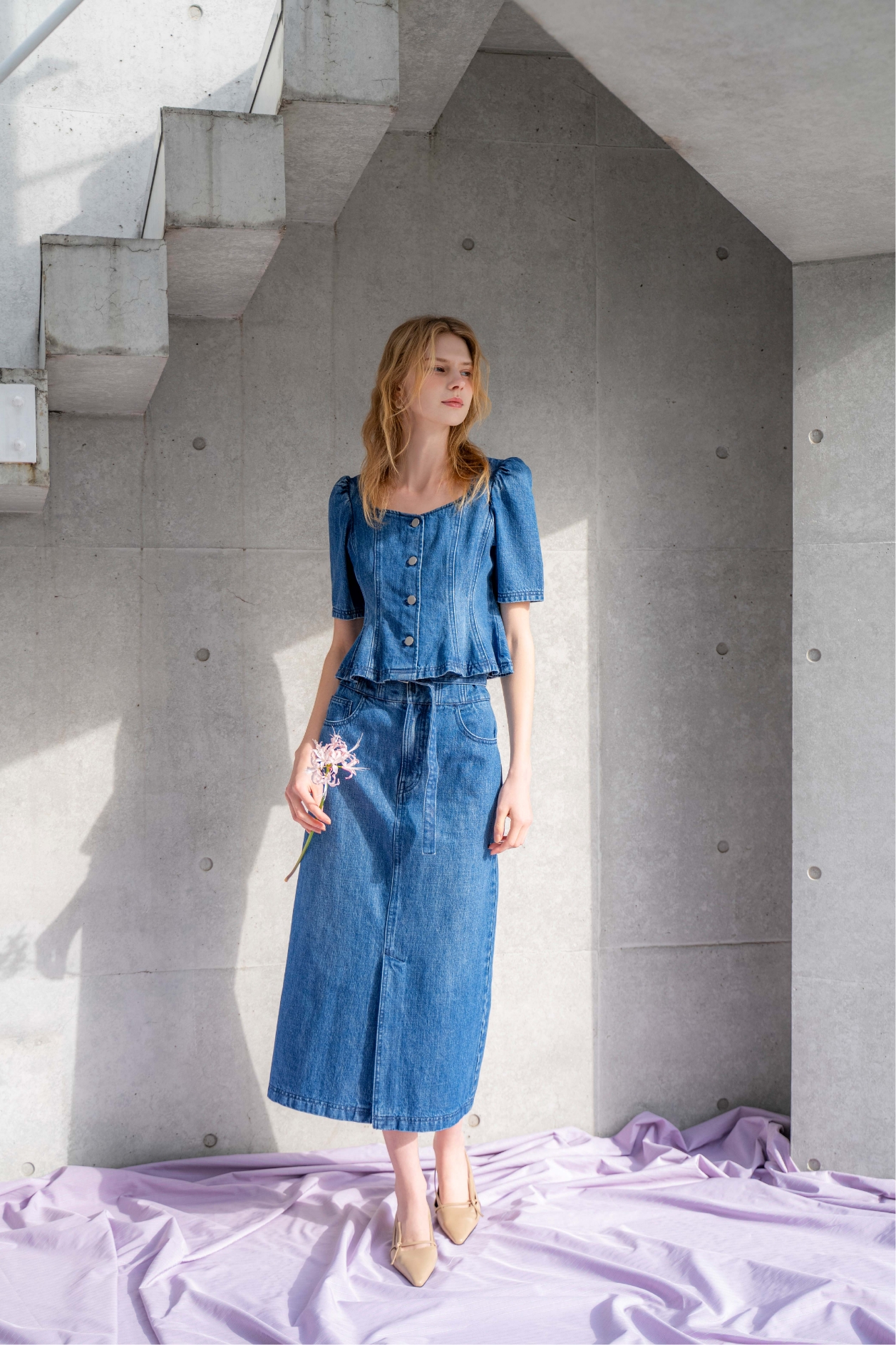 デニムフォルムトップス・デニムペンシルスカート・サイドノットパンプスを着用した女性