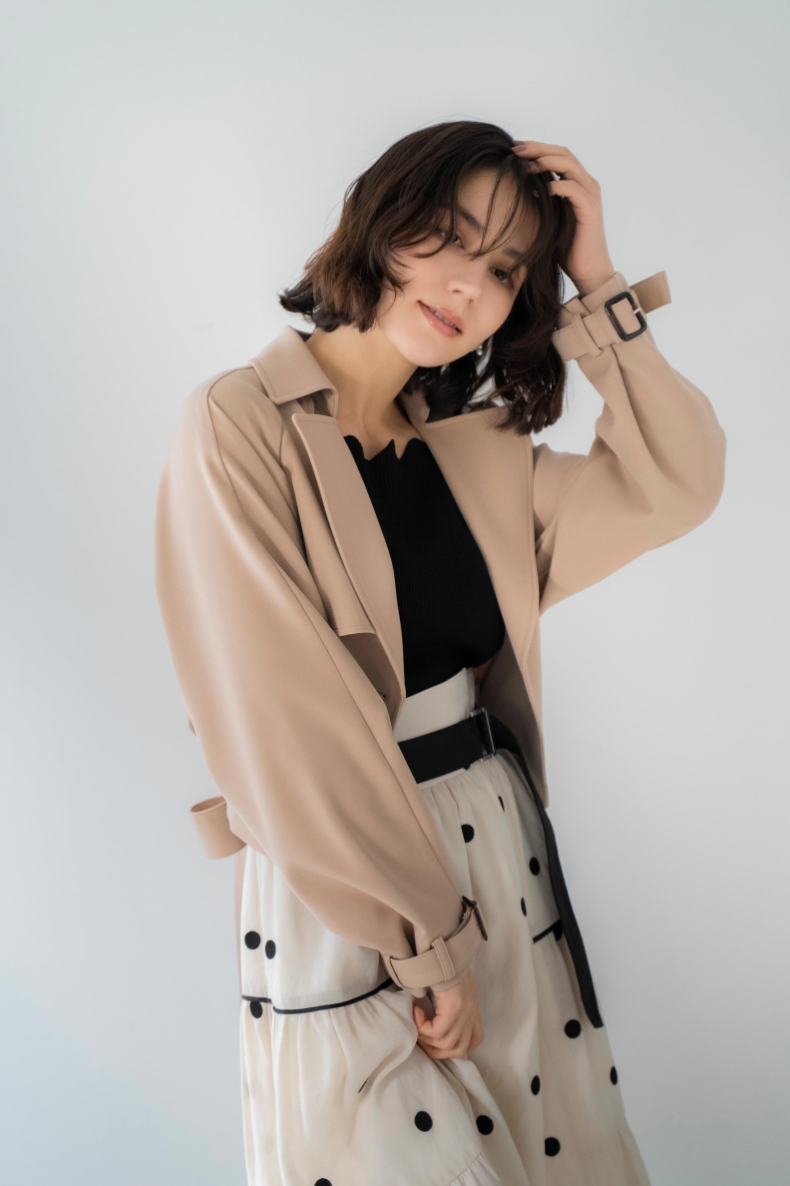 ラグランショートトレンチ・スカラネックデザインニット・ドット刺繍ティアードスカートを着用した女性の画像