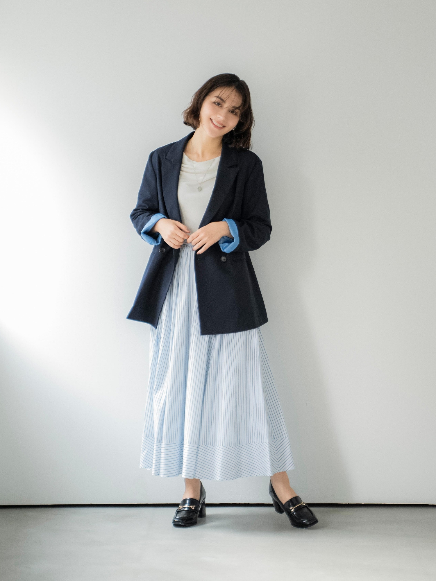 4Bダブルブレストジャケット・シアードレープカットソー・ストライプフレアスカート・スクエアビジューピアス・ニュアンスデザインネックレス・スクエアビットローファーを着用した女性の画像