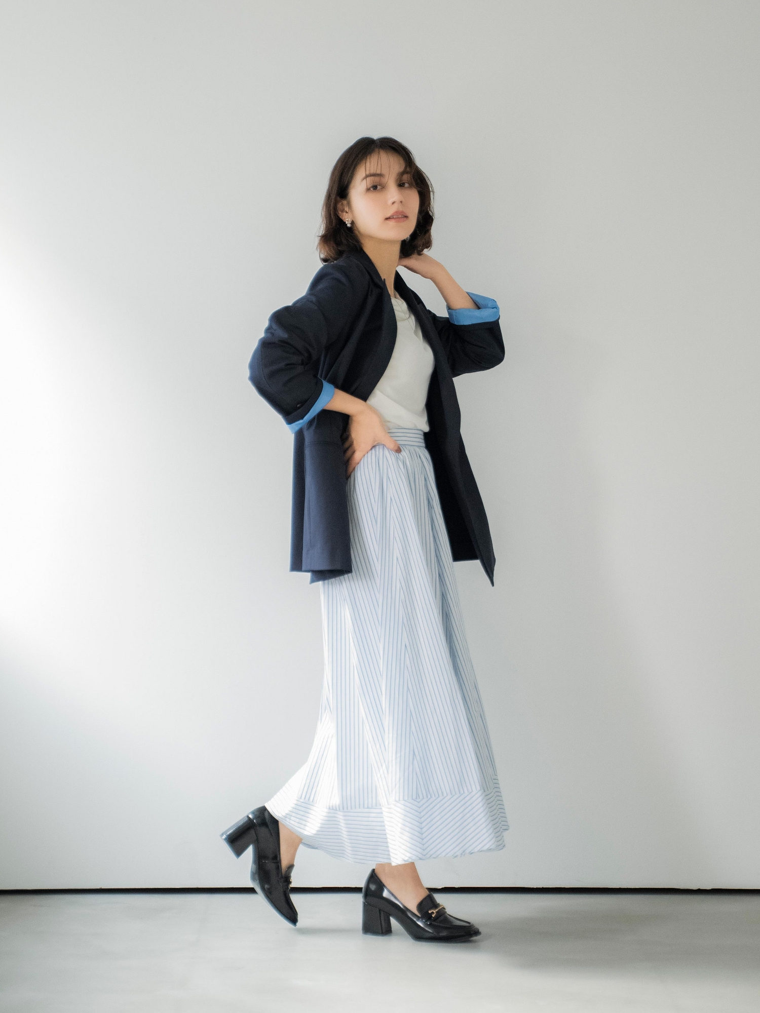 4Bダブルブレストジャケット・シアードレープカットソー・ストライプフレアスカート・スクエアビジューピアス・ニュアンスデザインネックレス・スクエアビットローファーを着用した女性の画像