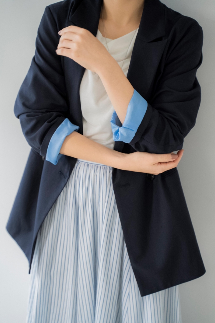 4Bダブルブレストジャケット・シアードレープカットソー・ストライプフレアスカート・スクエアビジューピアス・ニュアンスデザインネックレスを着用した女性の画像