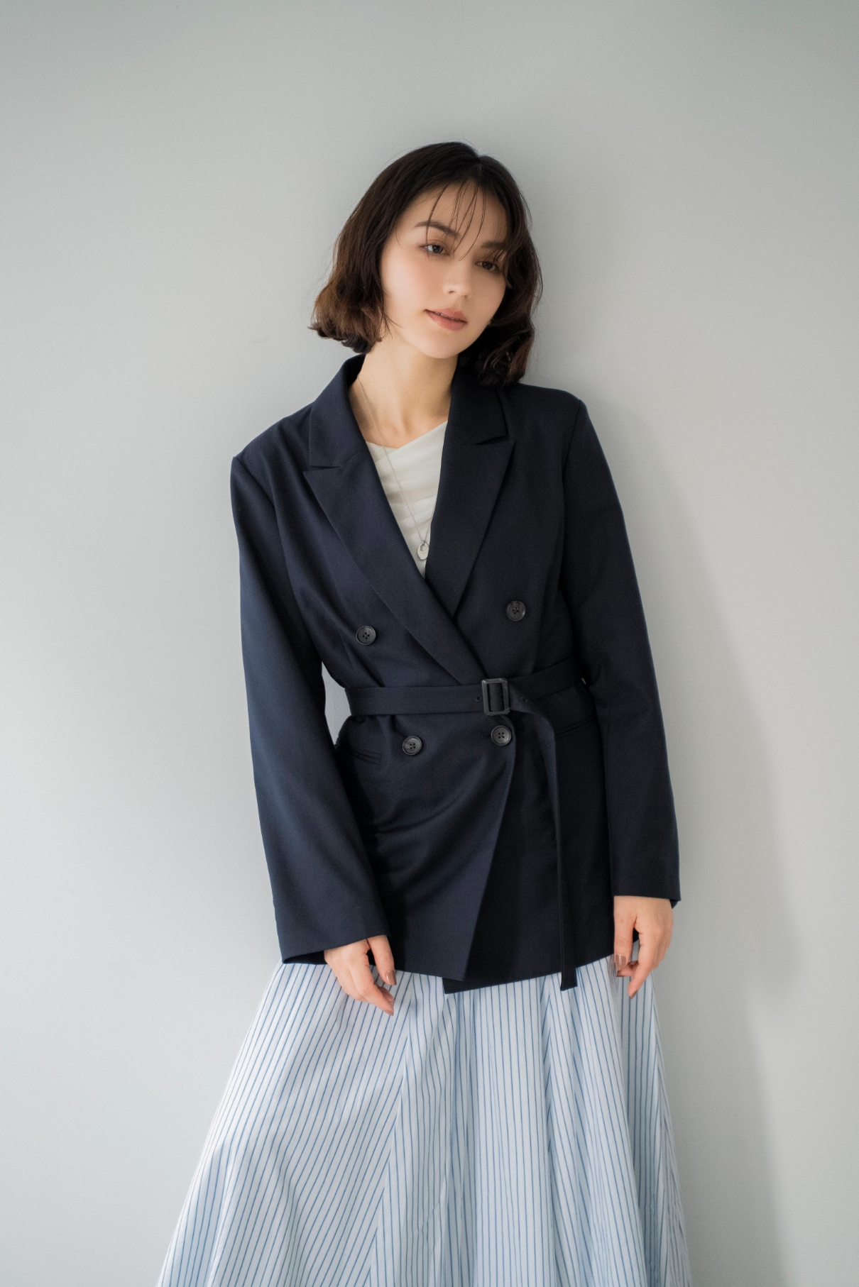 4Bダブルブレストジャケット・シアードレープカットソー・ストライプフレアスカート・スクエアビジューピアス・ニュアンスデザインネックレスを着用した女性の画像