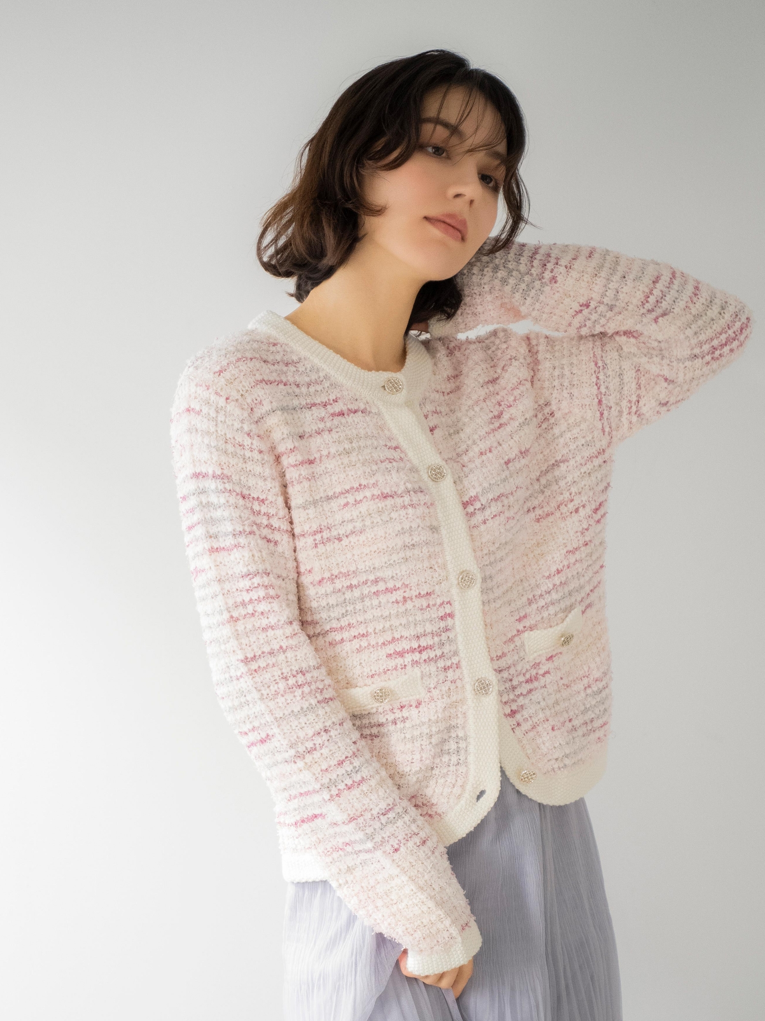 ツイードニットカーディガン・プリーツチュールスカートを着用した女性の画像