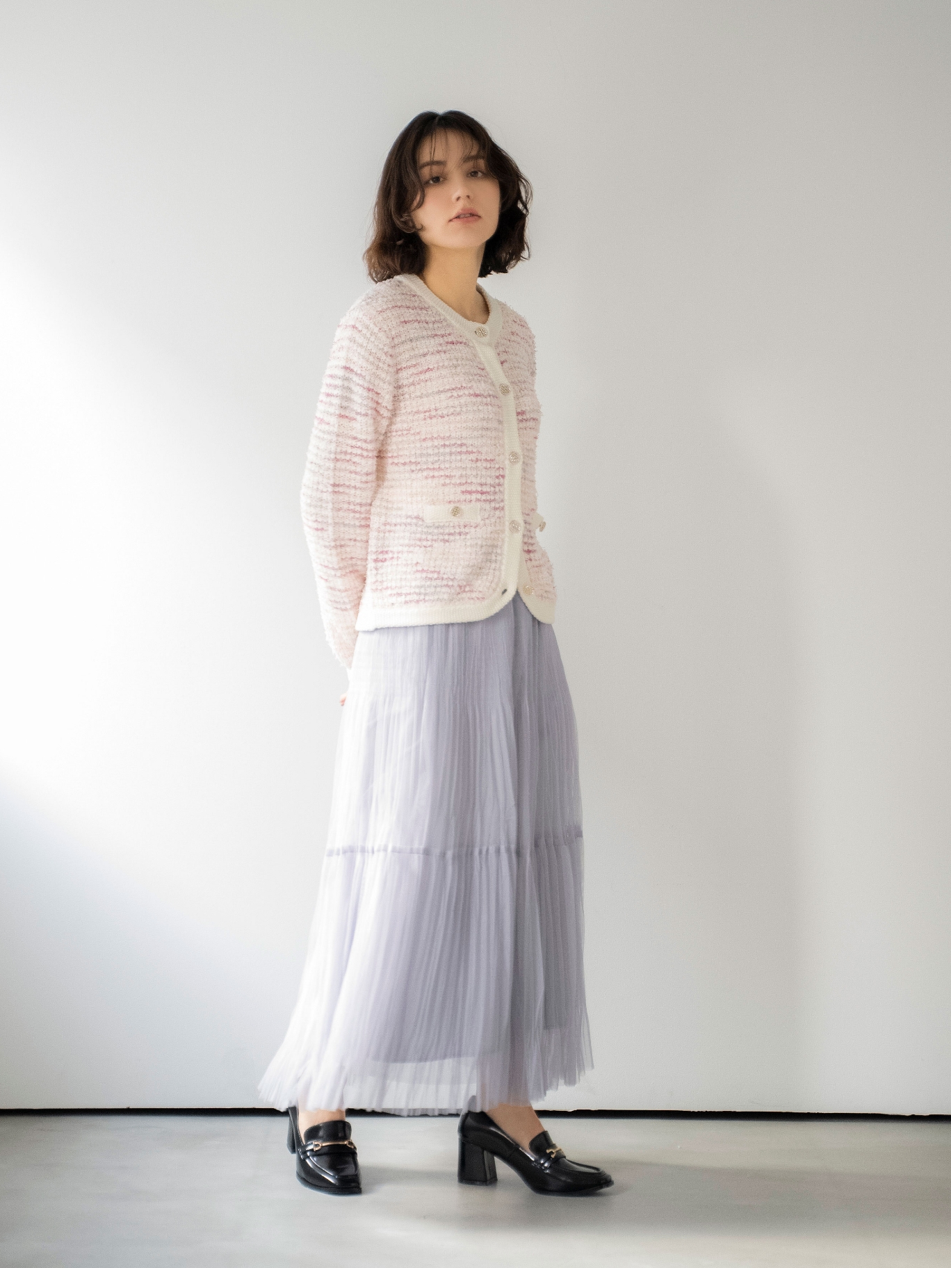 ツイードニットカーディガン・プリーツチュールスカート・スクエアビットローファーを着用した女性の画像