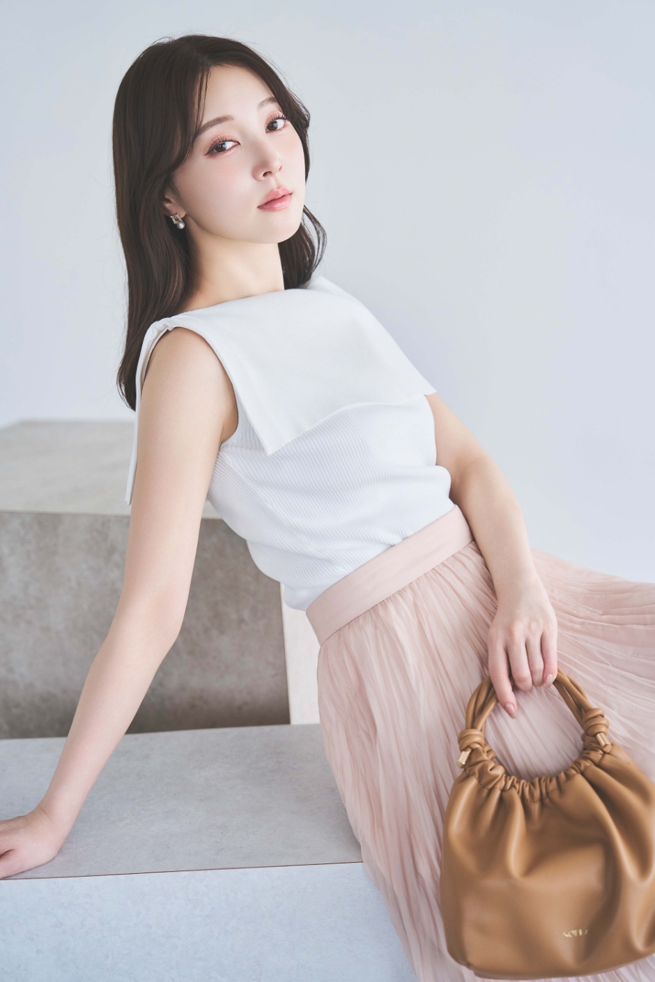 ２ＷＡＹドレープノースリリブニット・シアーランダムプリーツスカート・スクエアビジューピアスを着用した女性