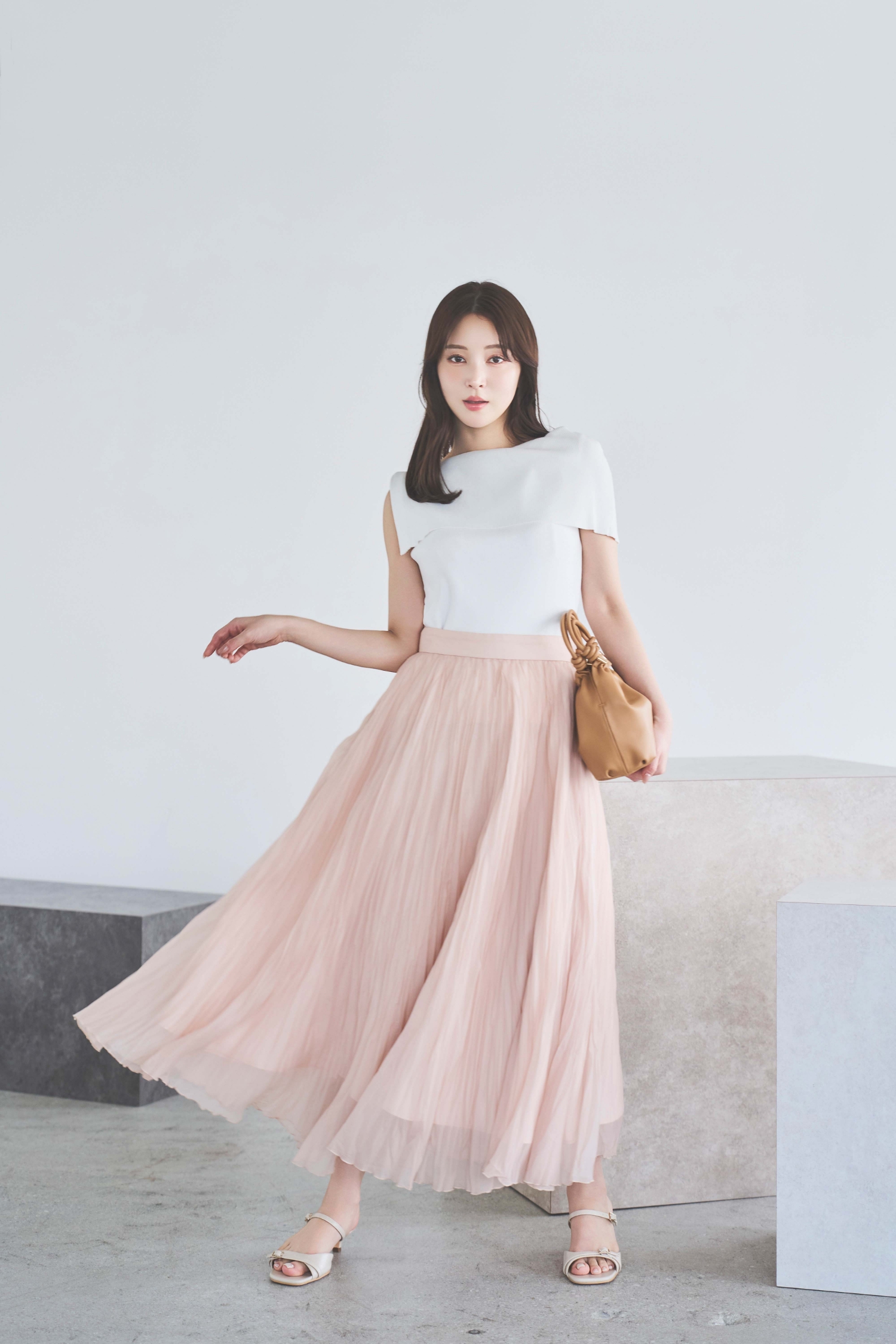 ２ＷＡＹドレープノースリリブニット・シアーランダムプリーツスカート・スクエアビジューピアスを着用した女性