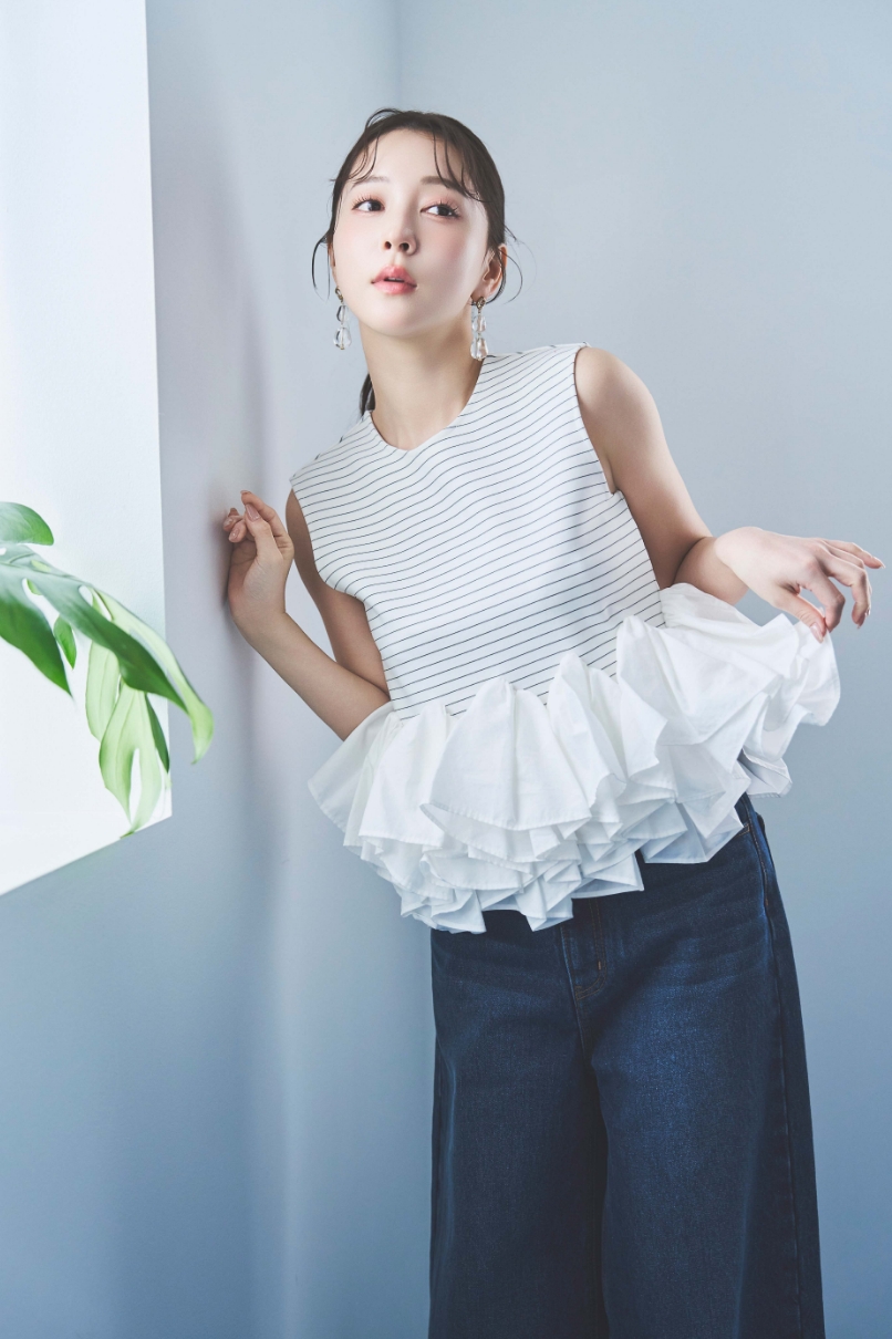 2wayノースリペプラムカットソー・デニムワイドパンツ・クリアモチーフピアスを着用した女性