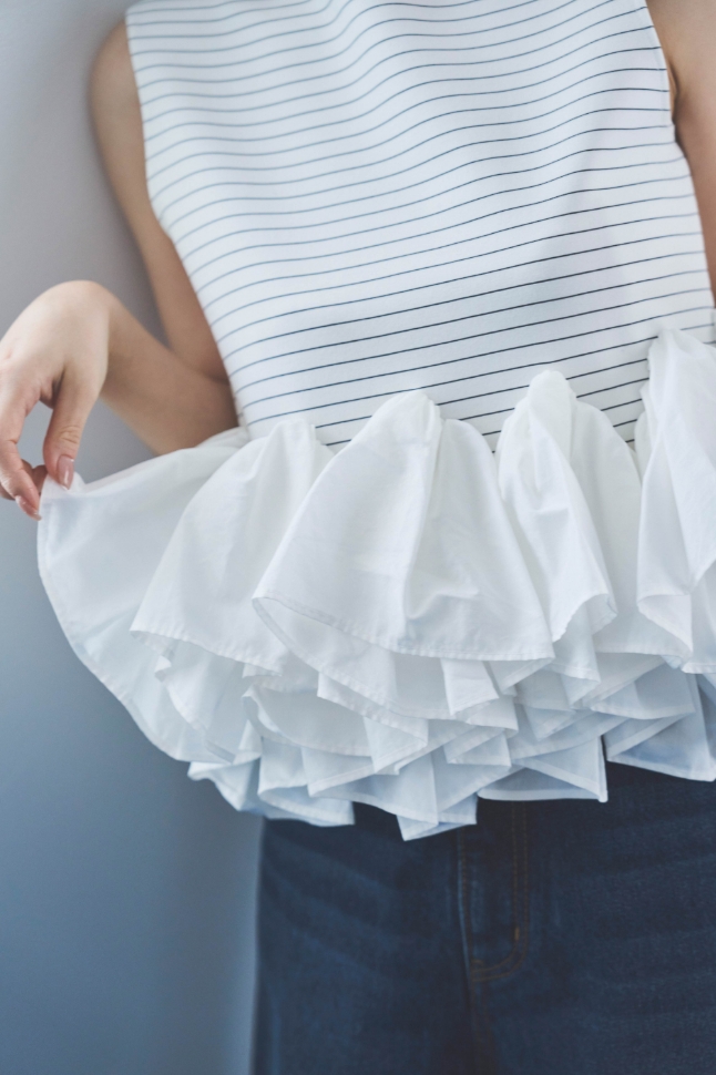 2wayノースリペプラムカットソー・デニムワイドパンツを着用した女性